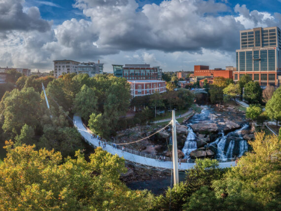 A bridge sweeps over a river before a cityscape