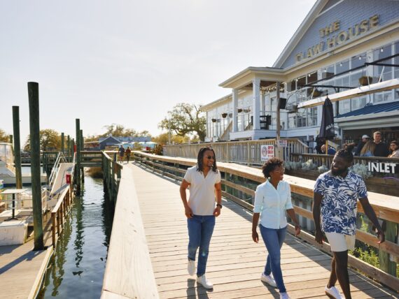 People stroll down a dock by the water