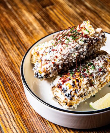 Corn on the cob with cheese and lime in a bowl