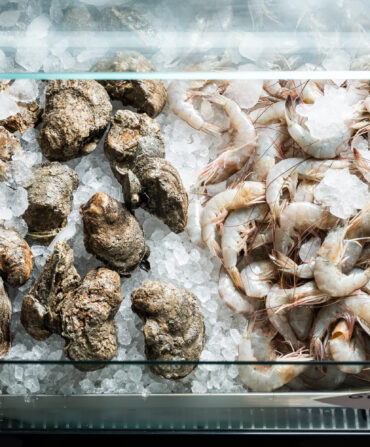 A display of fresh shrimp and oysters over ice.
