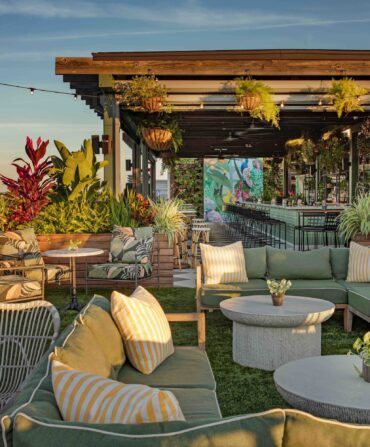 A rooftop bar filled with seating and plants