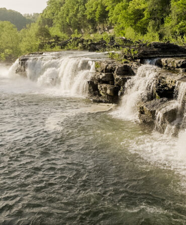An aerial shot of a waterfall in a forest