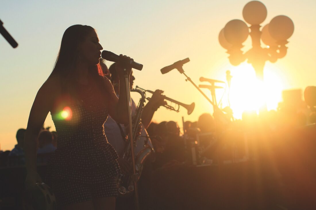 A woman singing into a microphone at sunset