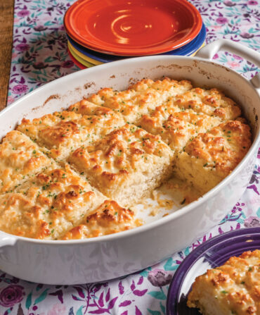 A white dish with biscuits inside. The dish sits on a floral tablecloth