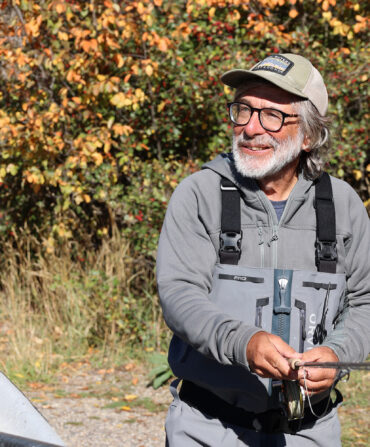 A fisherman on a river bank holding a rod