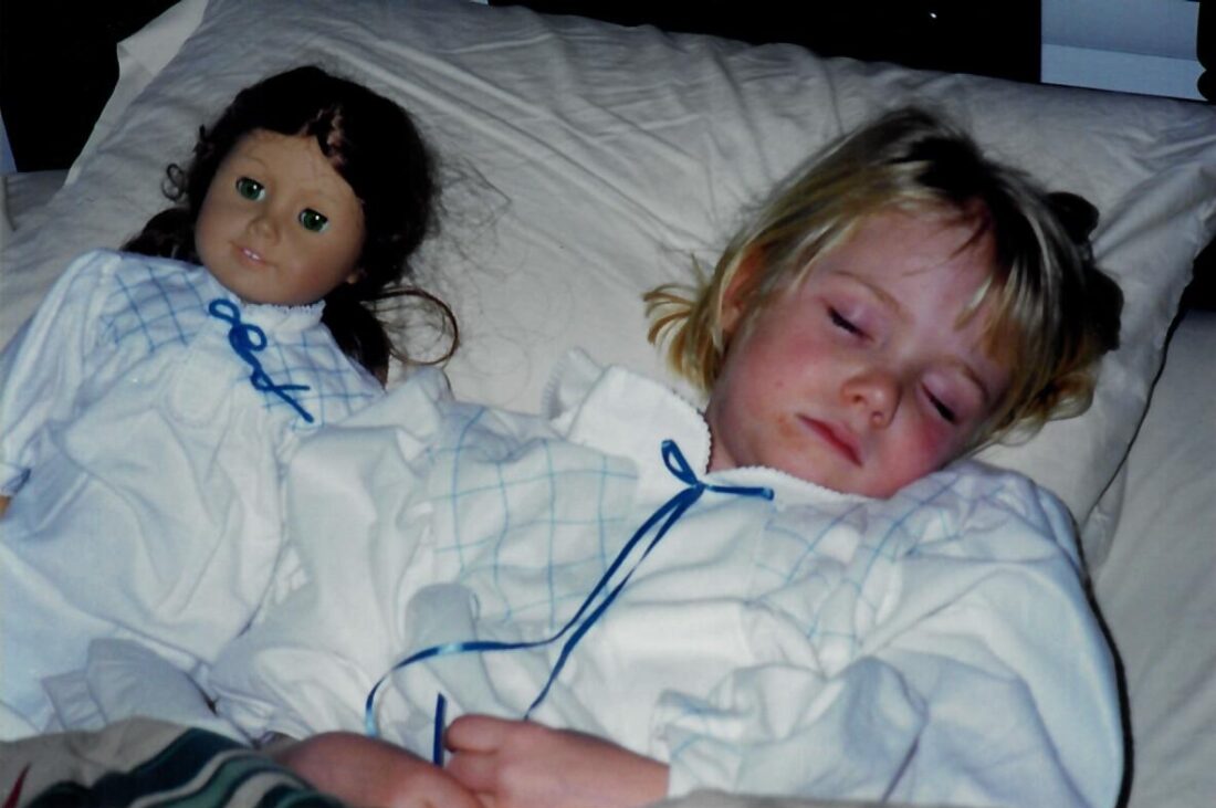 A girl and a doll in bed