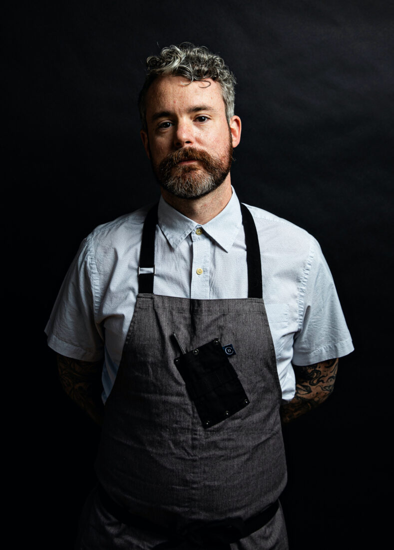 A portrait of a man with a dark grey apron