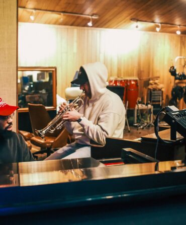 A group of three men work in a music studio