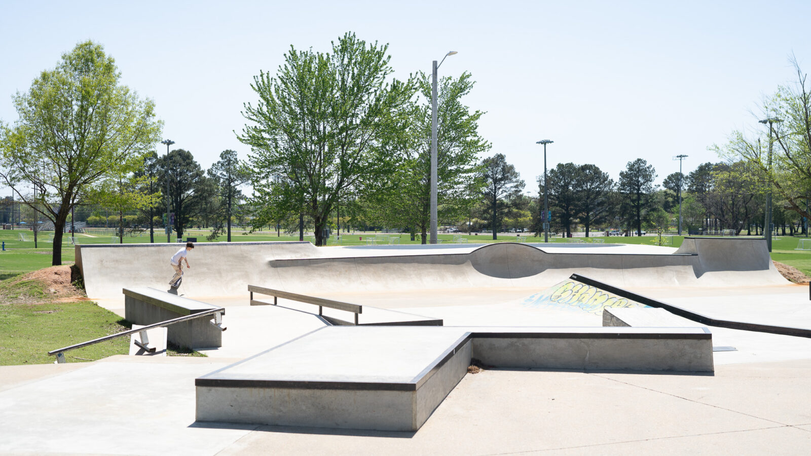 A skateboarder glides down a halfpipe at an outdoor skate park