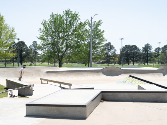 A skateboarder glides down a halfpipe at an outdoor skate park