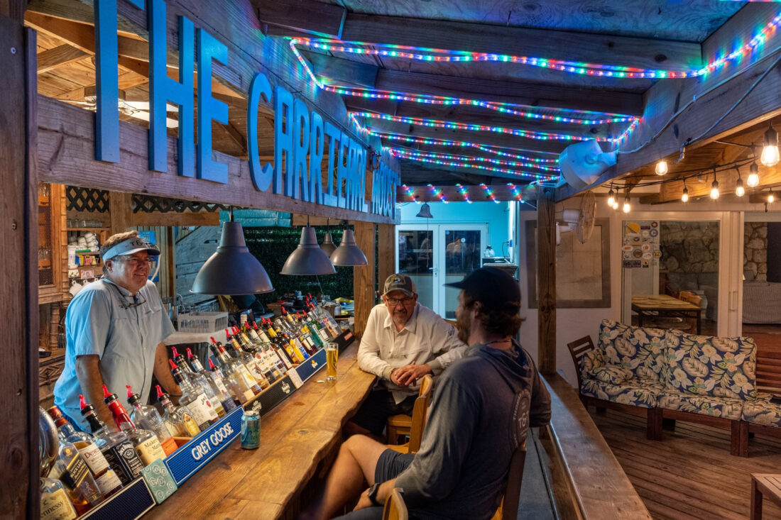 Men sit at a bar in a coastal setting