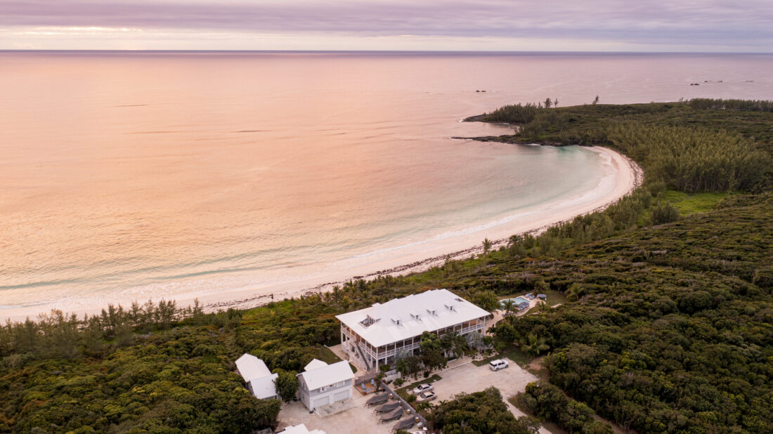 A lodge on the beach with a pink sunset