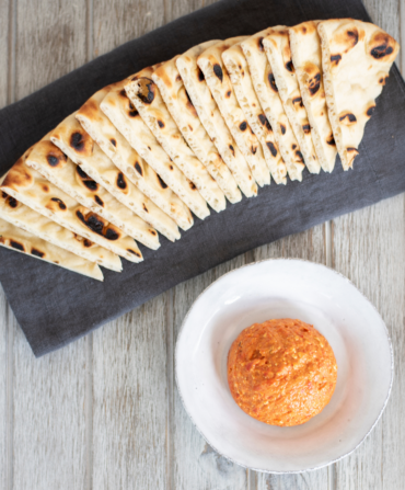 A tray of pita bread and a bowl of roasted red pepper spread